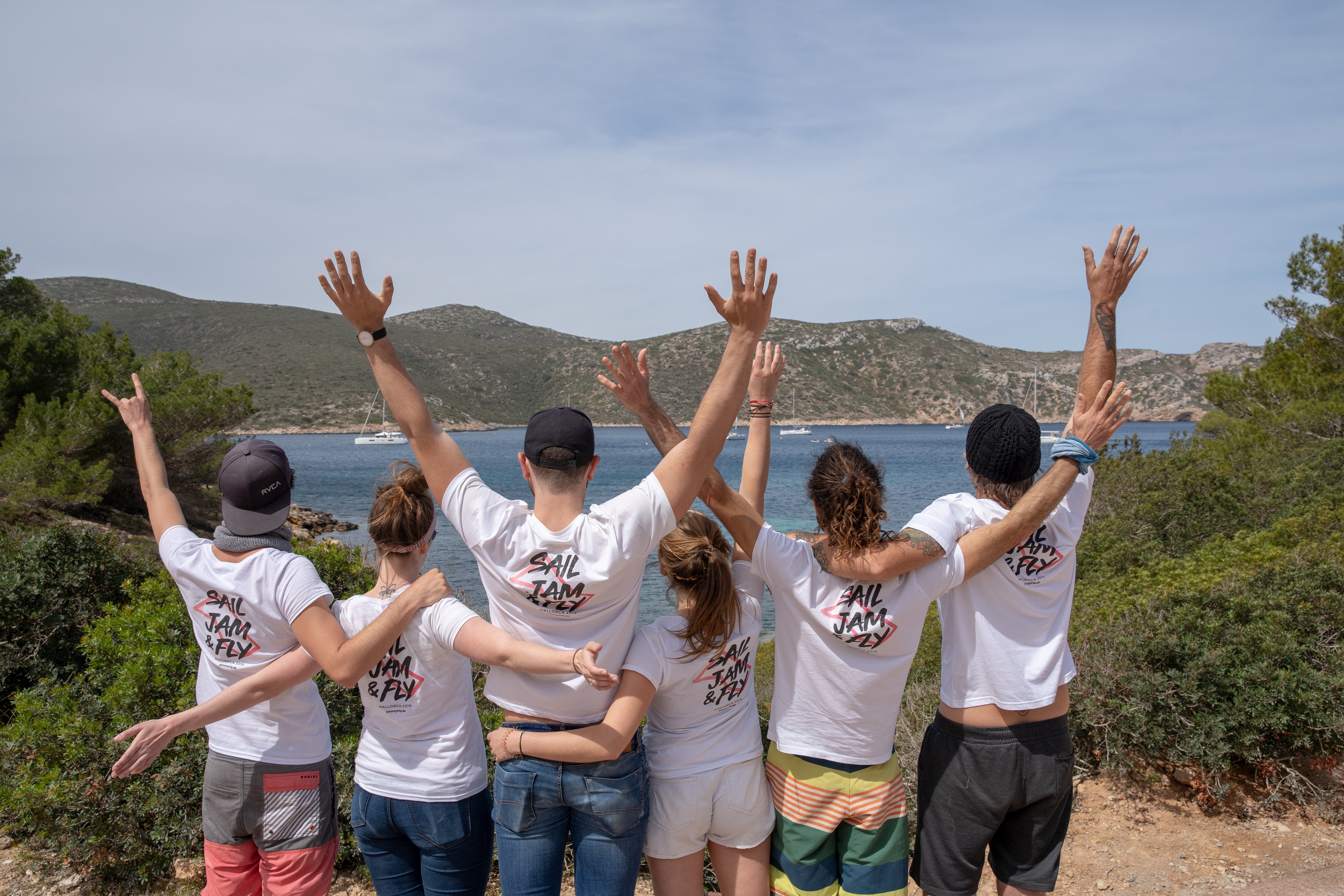 Group of people with arms around each other looking out on to a lake