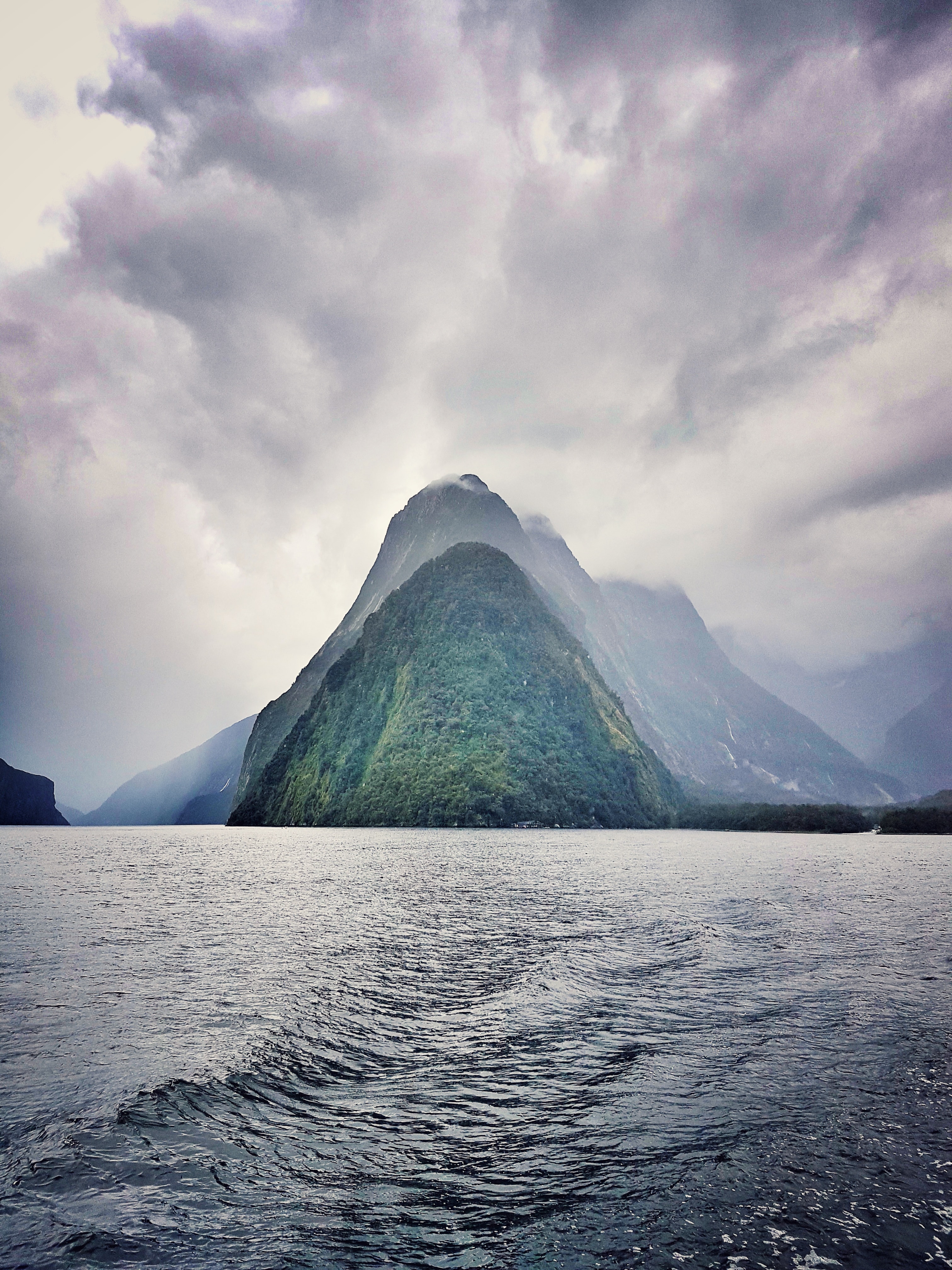 The impressive scenery of Fiordland National Park in New Zealand with mountains in the background and a wild river in the foreground. 