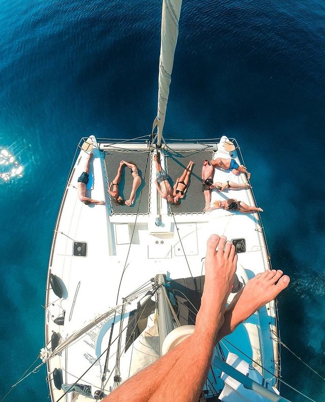 Picture of feet from above a sailboat with people laying on the deck 