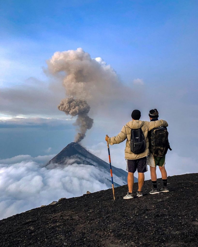 Volcano in background with two hikers from a group of travelers