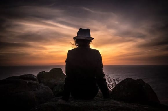 Women sitting on rocks watching the sunset over the ocean