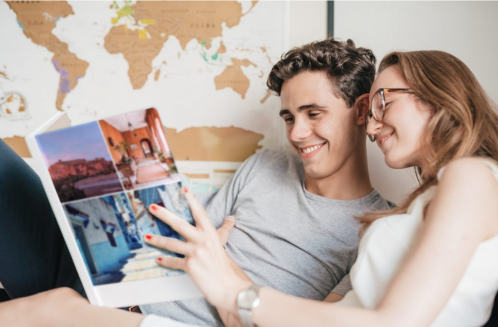 A man and a woman looking at a Journi phonebook with a smile while laying in bed together. 