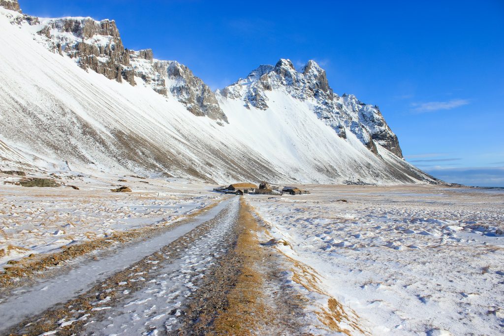 An insider tip for Iceland is to visit the Viking village film set in Stokksnes, Iceland with the mountains covered in snow with a blue sky.