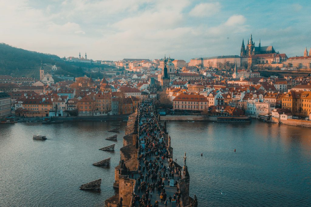 A city view of Prague, Czech Republic in the day time with people crossing a bridge.