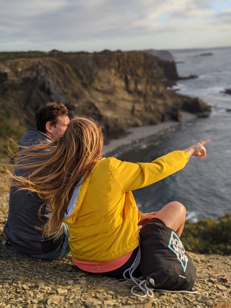 Two people by seaside cliffs at sunset