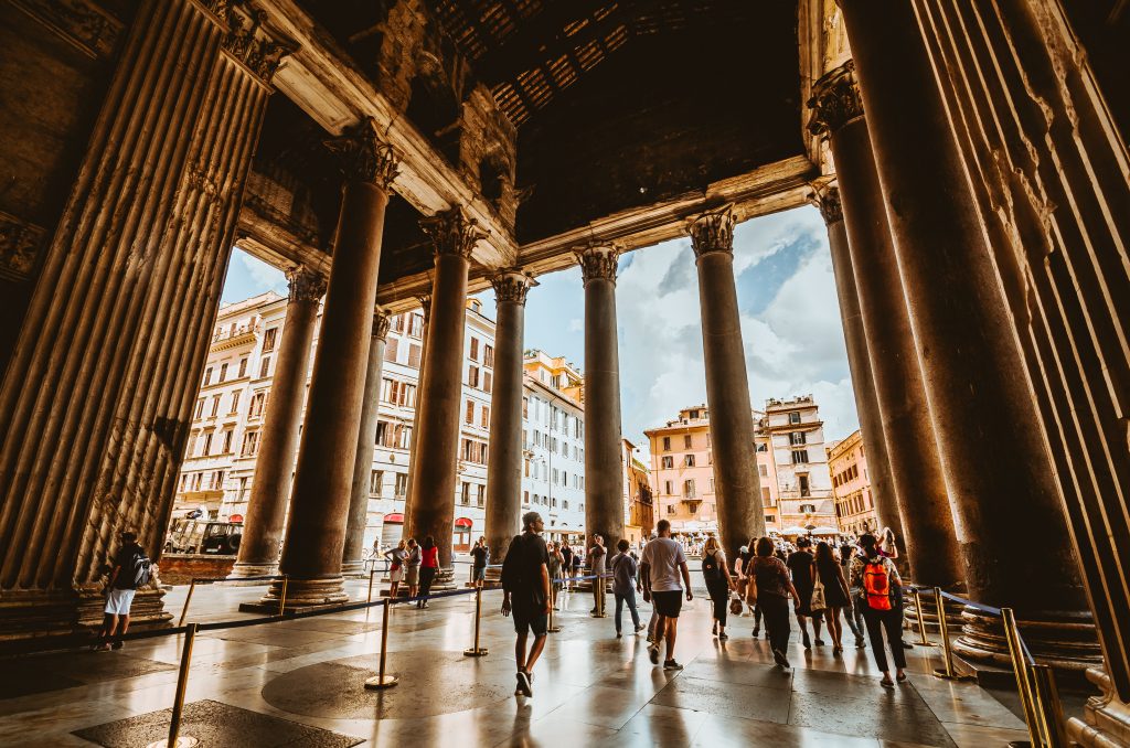 Pantheon is one of the best places to visit in Italy with high pillars and people wandering around looking.