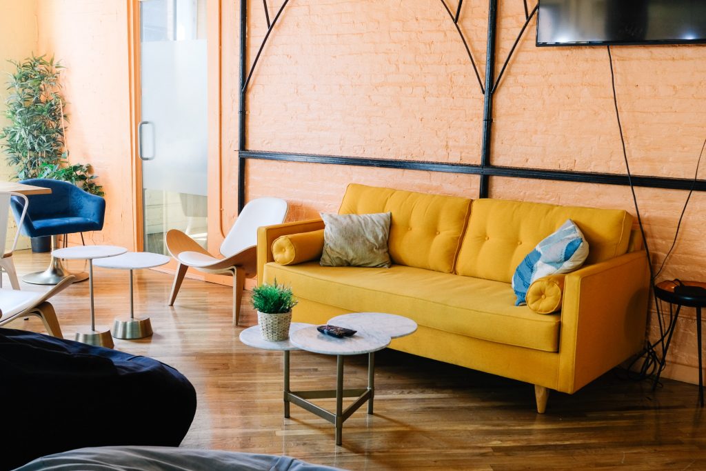 An office room with a yellow couch and white coffee table placed infront of it. 