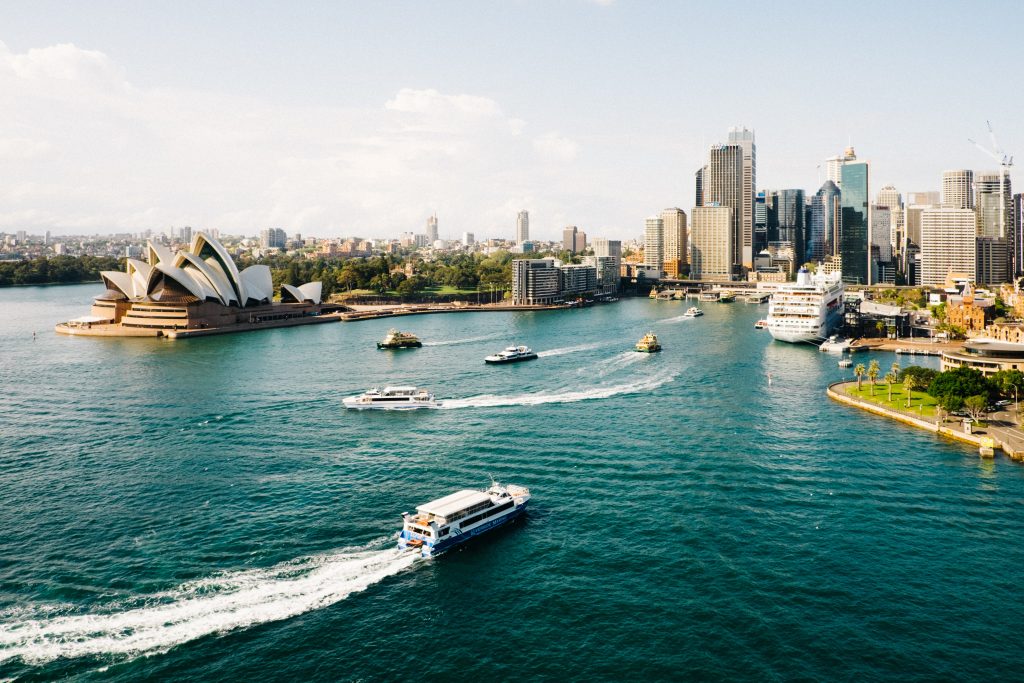 Australia with a city view and a boat driving in the ocean.