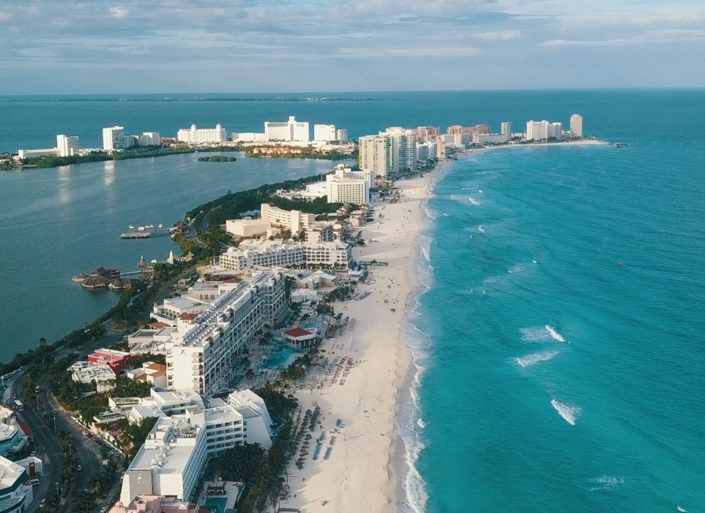 The coast line of Cancún with lots of hotels lining the beach and blue water either side of it.