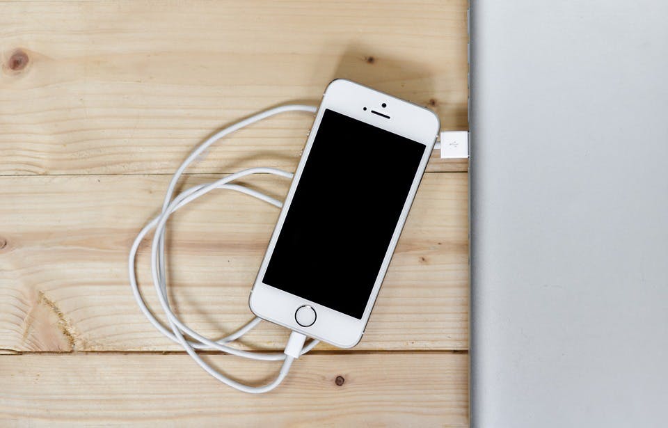 a phone charging with its cable onto a laptop