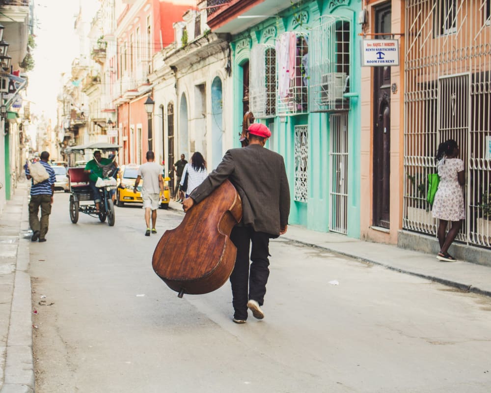 Man carrying a cello while walking down a street the best travel movies and books