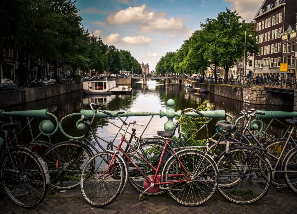 bikes parked infront of a bridge with a view of the Amsterdam canal.