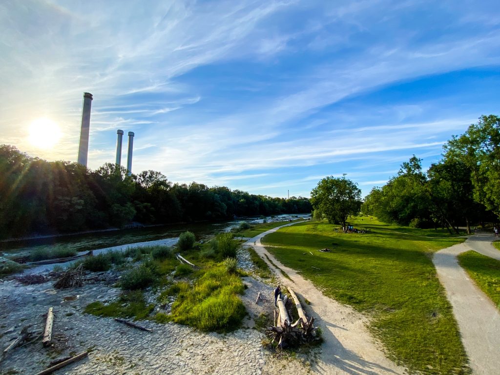 a view of the tsar river in Munich during the day time with clear blue sky and green grass.