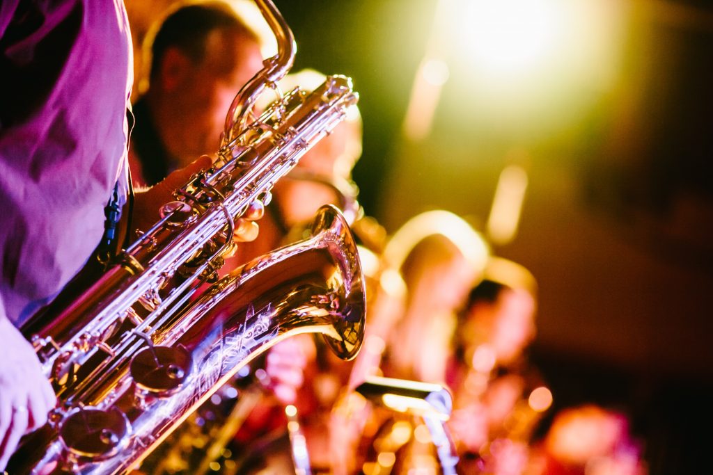 Men playing the saxophone with bright lights.