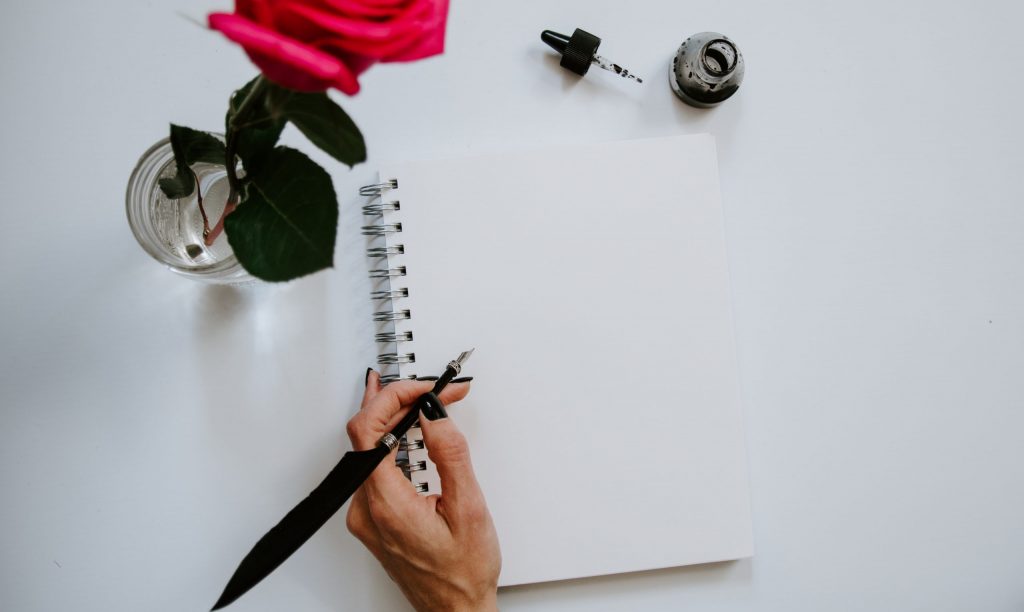 a woman about to write a bucket list with a red rose during winter lockdown