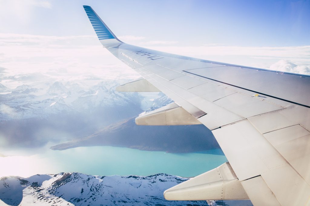 A Plane in the sky flying over icy mountains and snow.