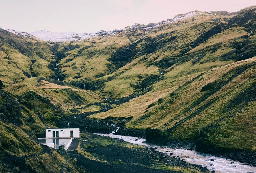 Seljavallalaug pool in Iceland with a green mountain view.