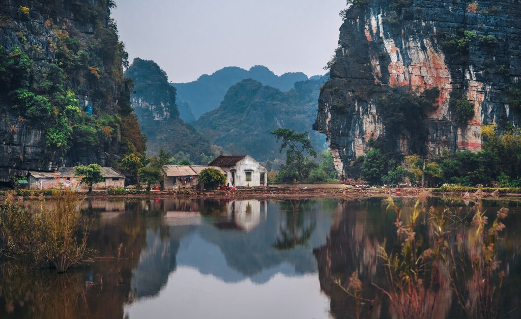 A view of vietnam with a  small white house by the water.