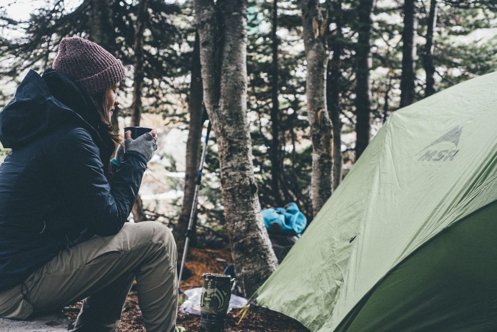 Girl eating in a forest by a tent