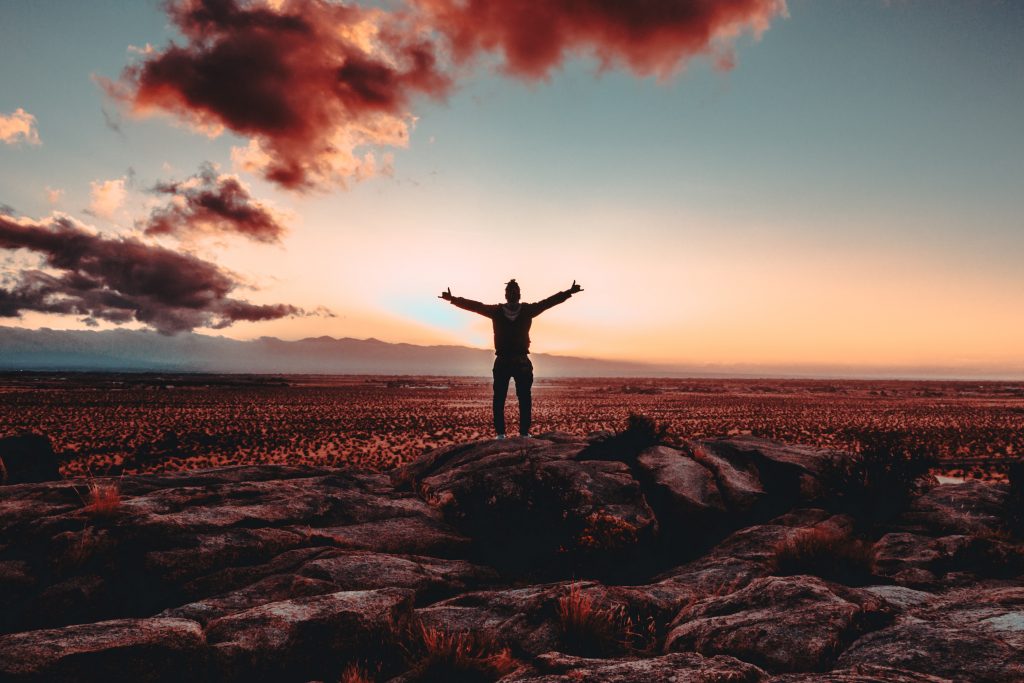 A man standing on top of rocks with both his hands up in the air.