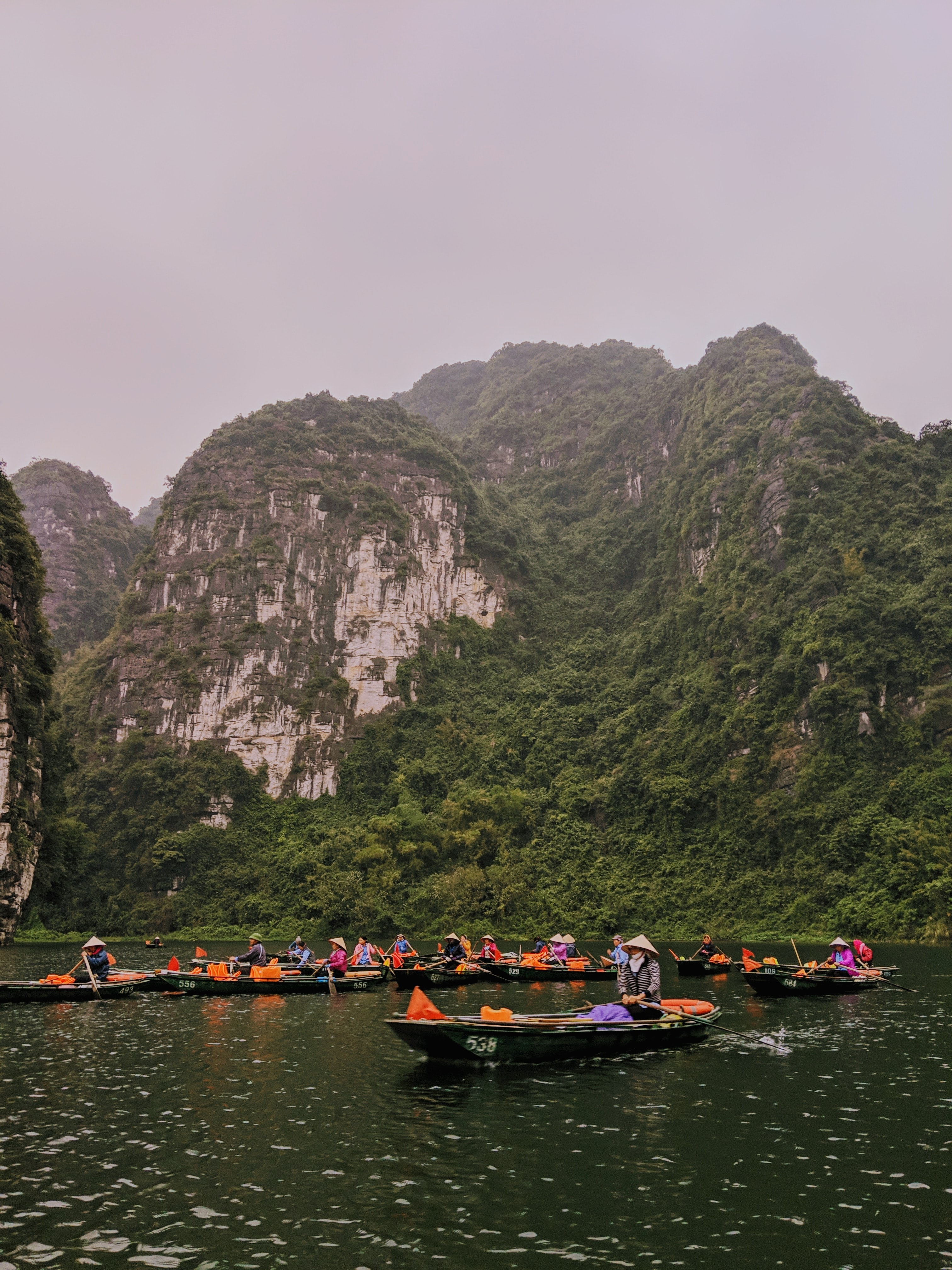 A boat tour in Trang an, Vietnam with orange flags on the boats.