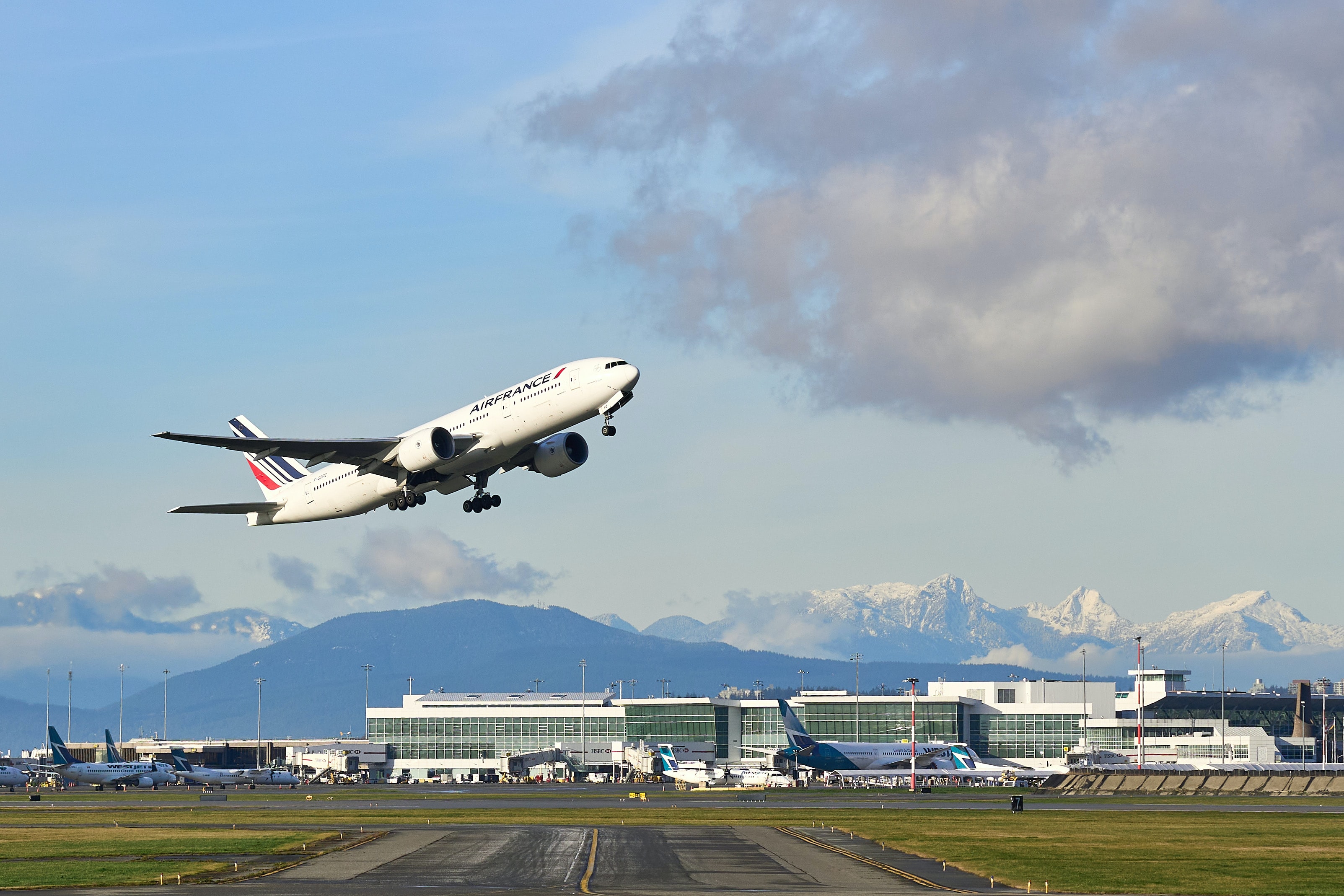 A plane taking off with mountains and Vancouver airport in background