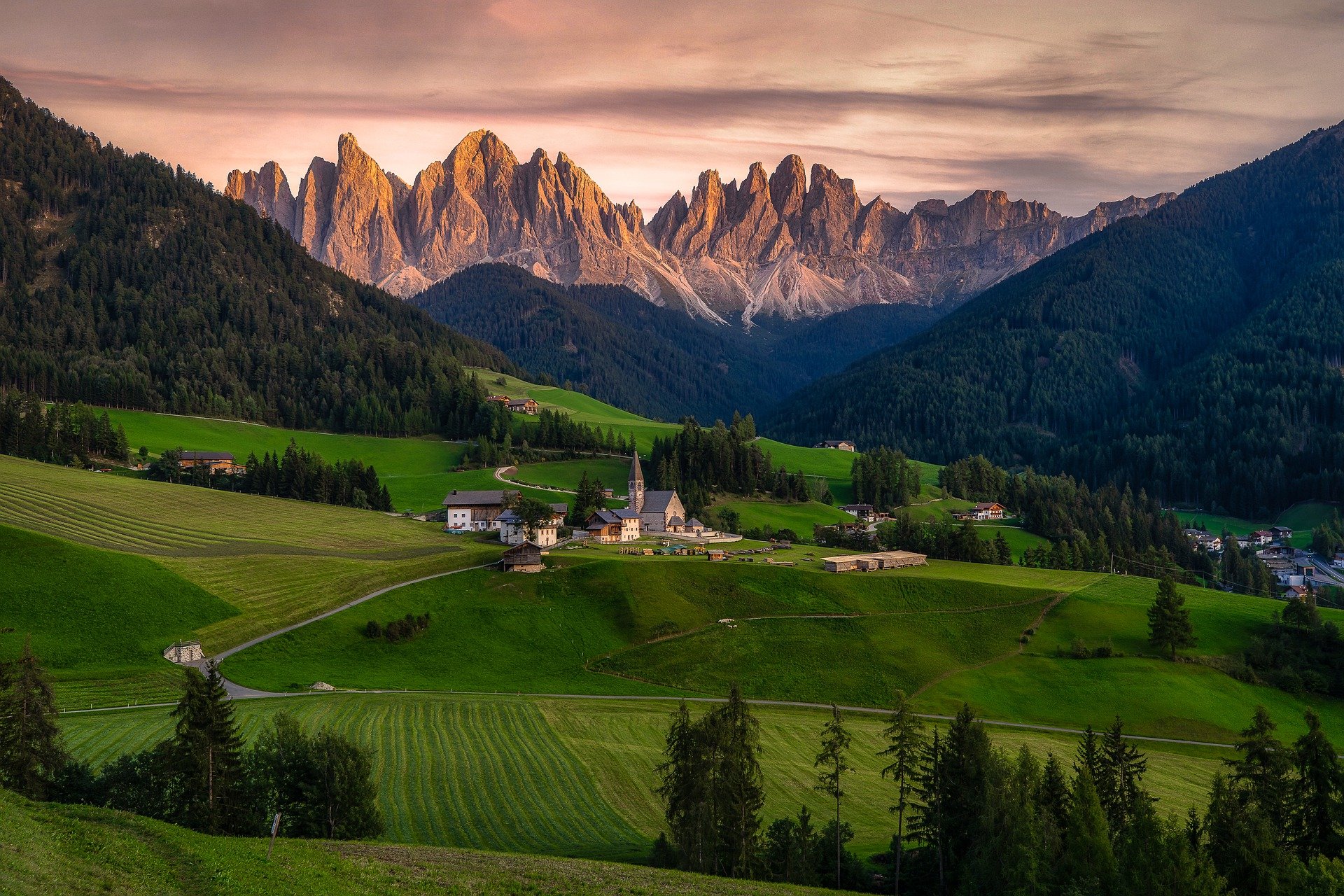 Rolling hills with a small village and mountain background