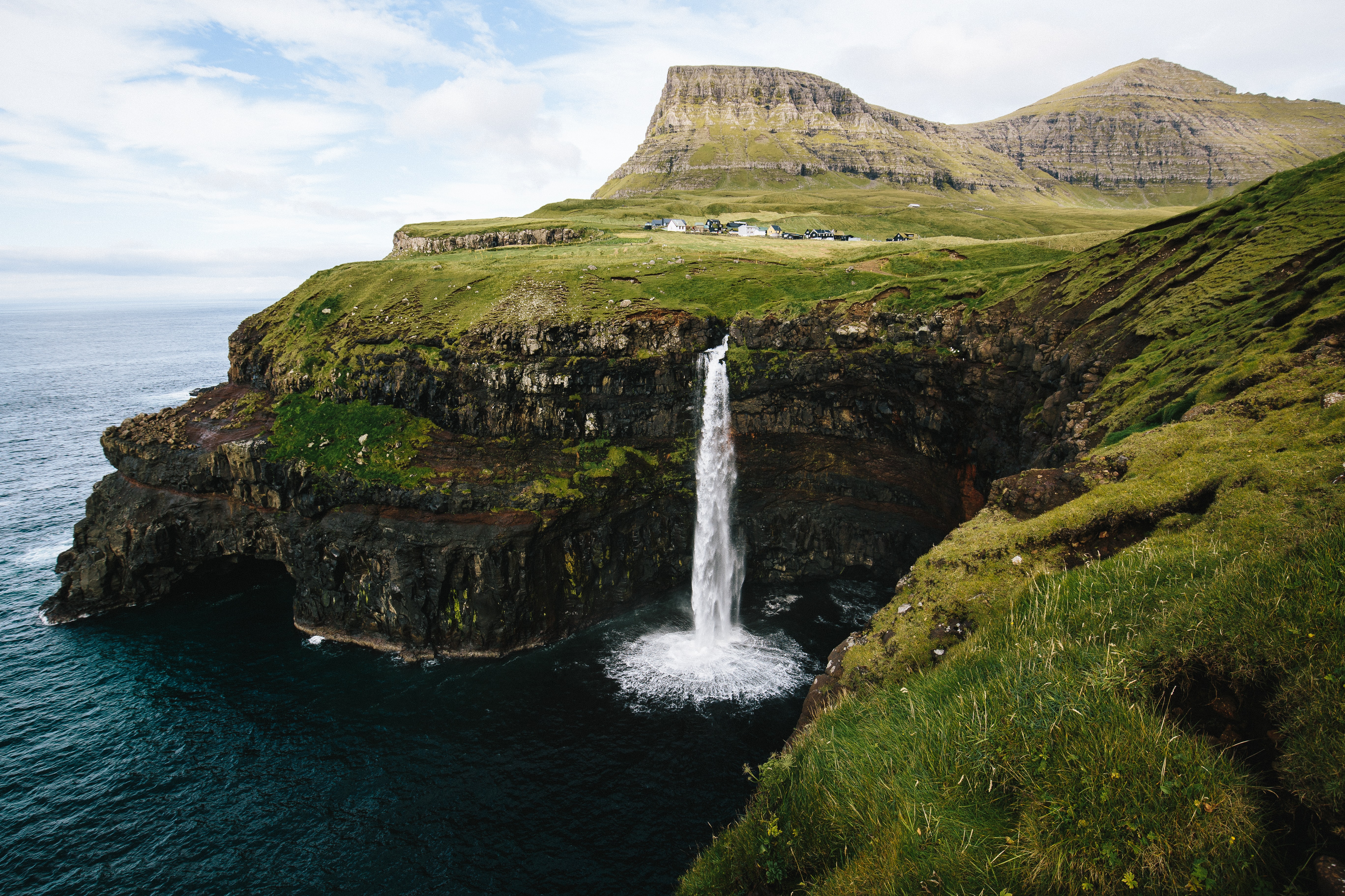 Waterfall falling into the ocean from high rocky cliffs