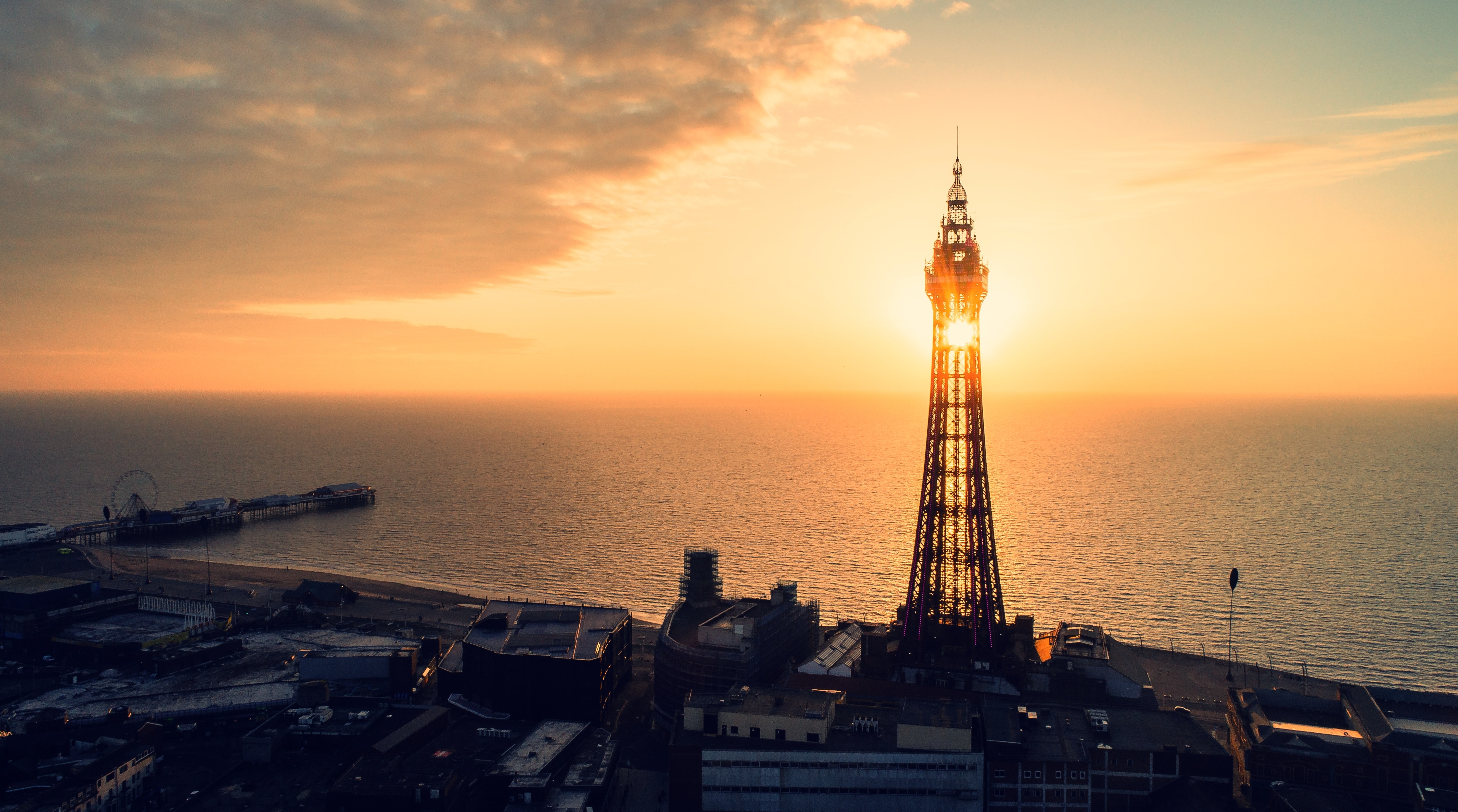 A tower in the sunset at the sea. In the background you can see a Ferris wheel.