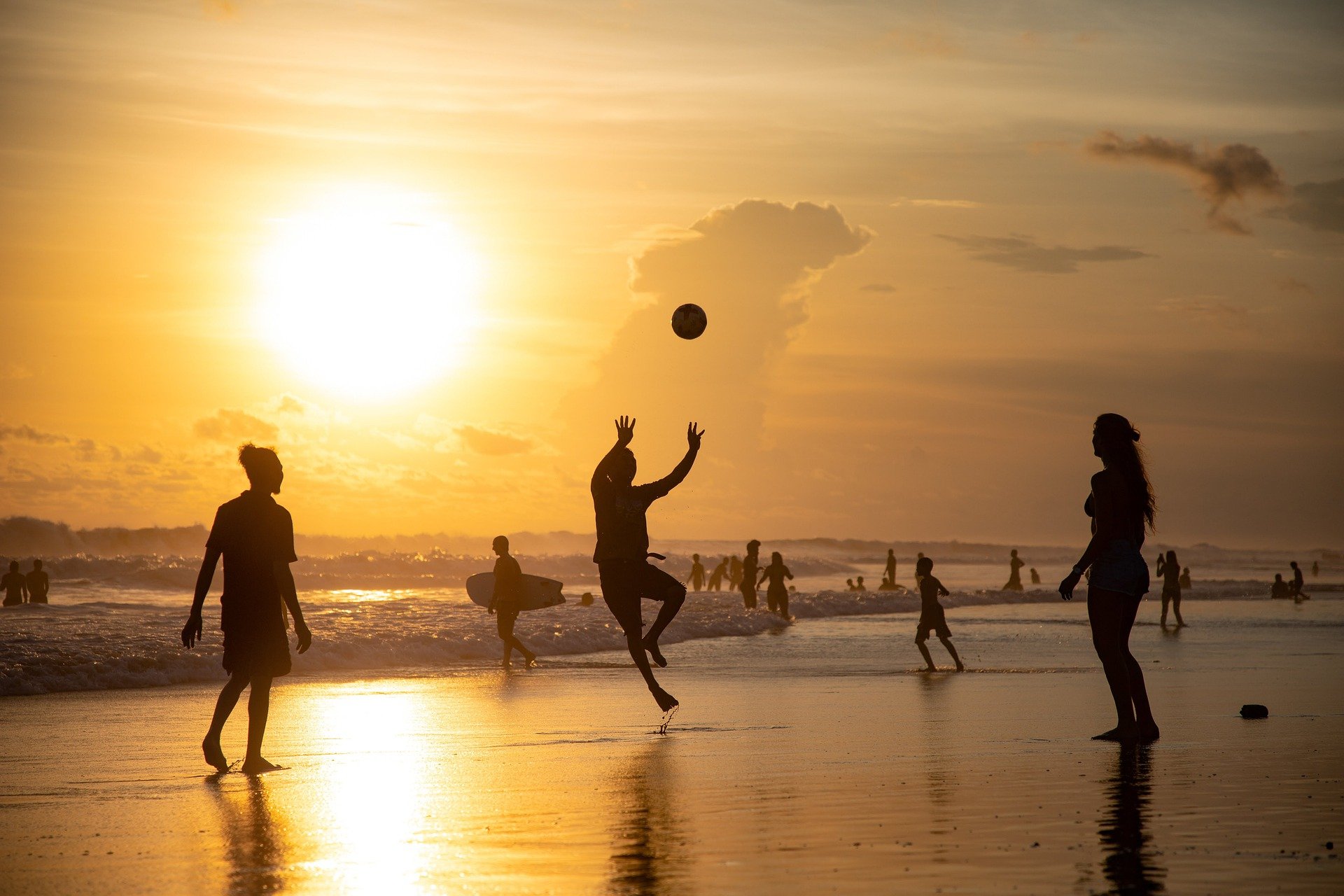 People playing volleyball on beach at sunset