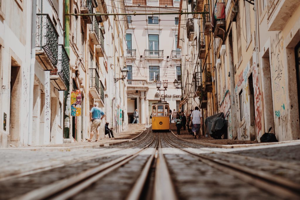 Yellow tram traveling through the streets of Lisbon