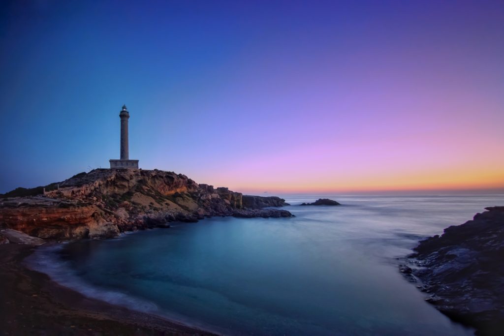 beautiful sunrise with a lighthouse by the coast