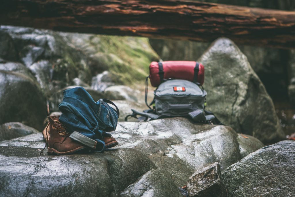 hiking bag and hiking boots on rocks in the nature