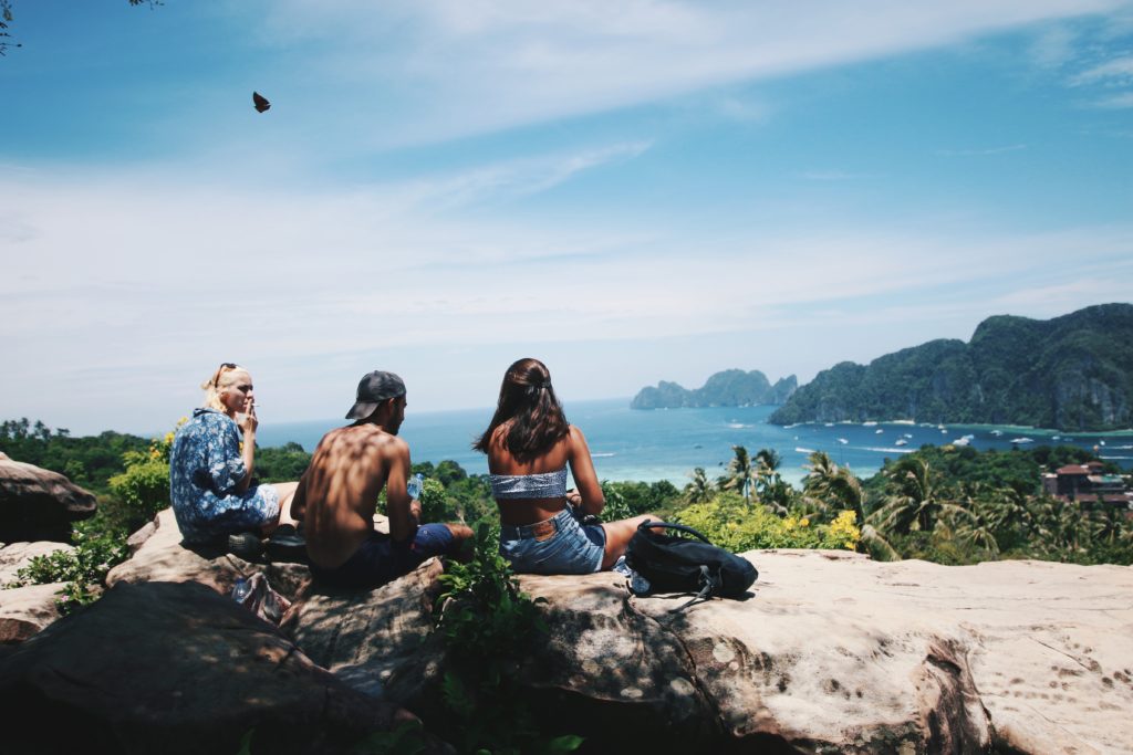 travel buddies sit on rocks near coast in europe