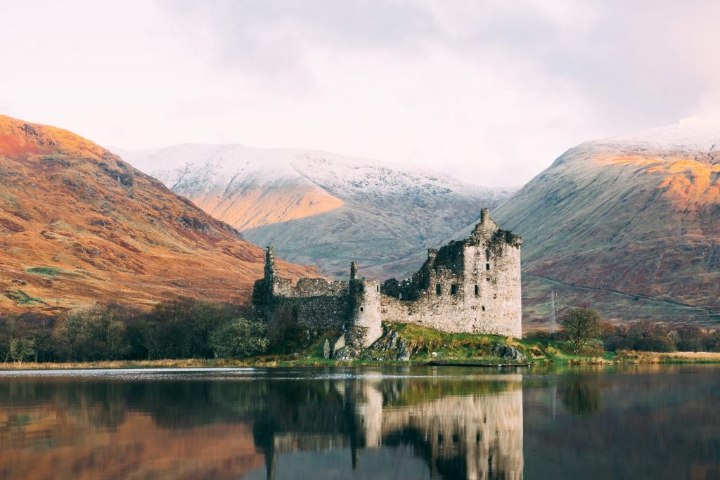 Castle in Scotland on a lake with hills in the background