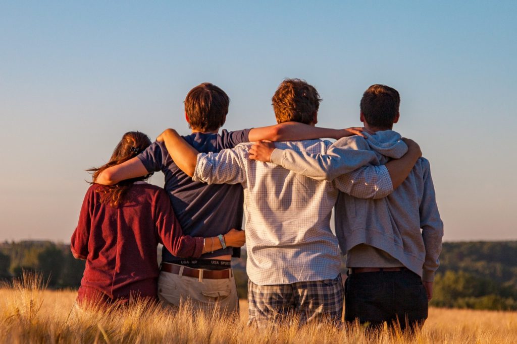 4 friends hugging standing in a fiels 