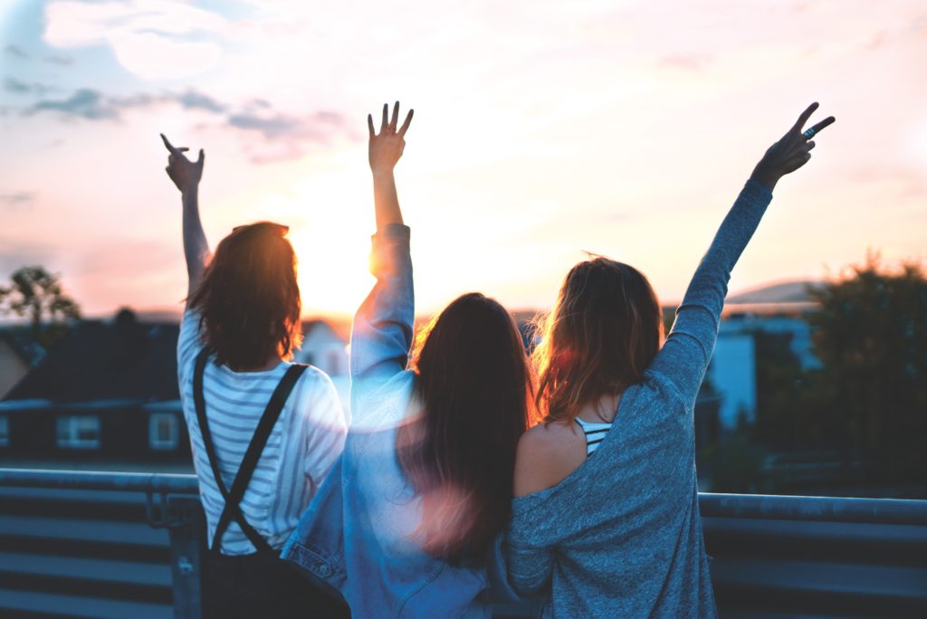 how to be the perfect trip leader - three girls standing with back to camera with their hands up 