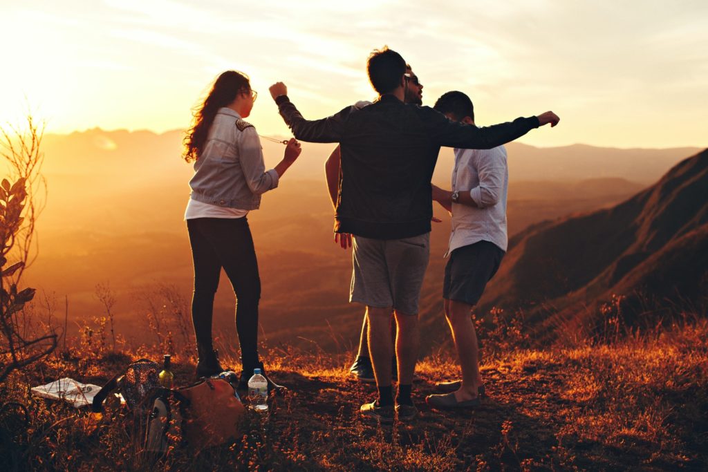 group of friends standing together and dancing in the beautiful sunset 