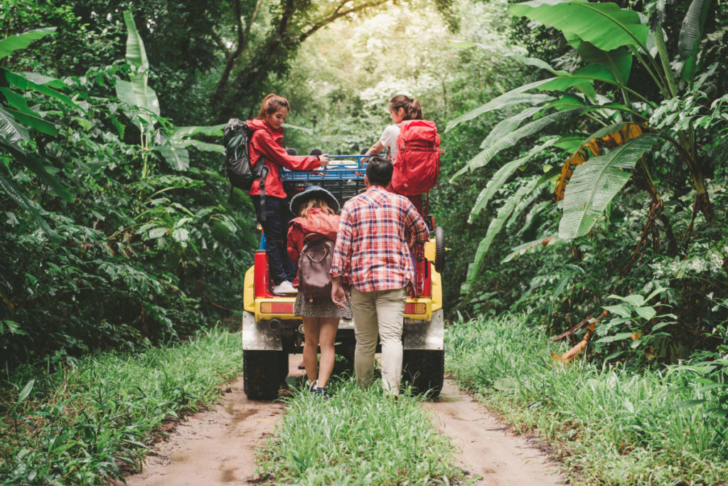 Four people on a jeep driving through the forest