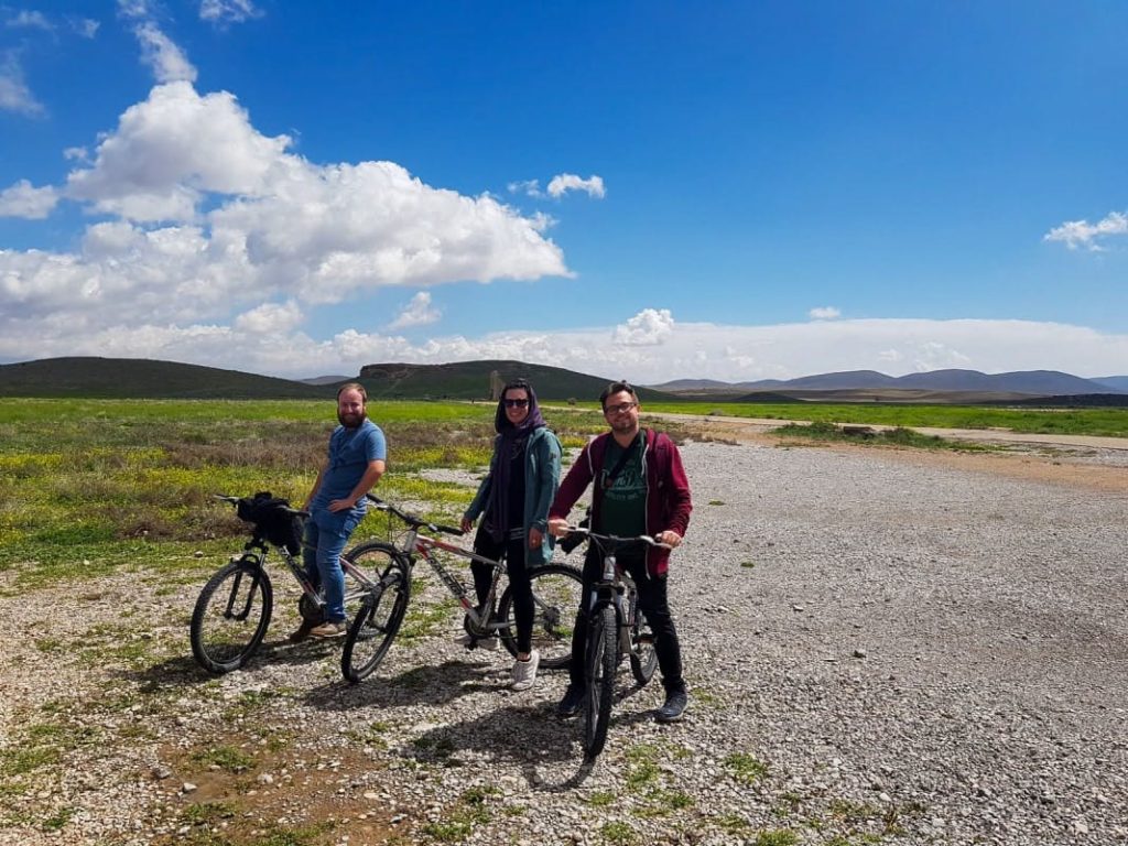 A group of 3 people on a bike out on a field