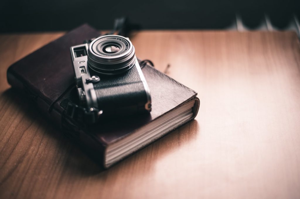 A camera lying on top of a photo album things to do during the coronavirus lockdown