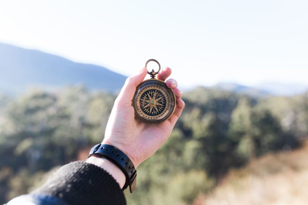 man holding a compass in his hands to become a TripLeader