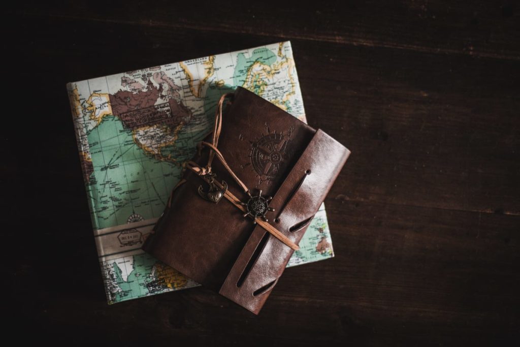 a little leather brown notebook laying on top of a world map