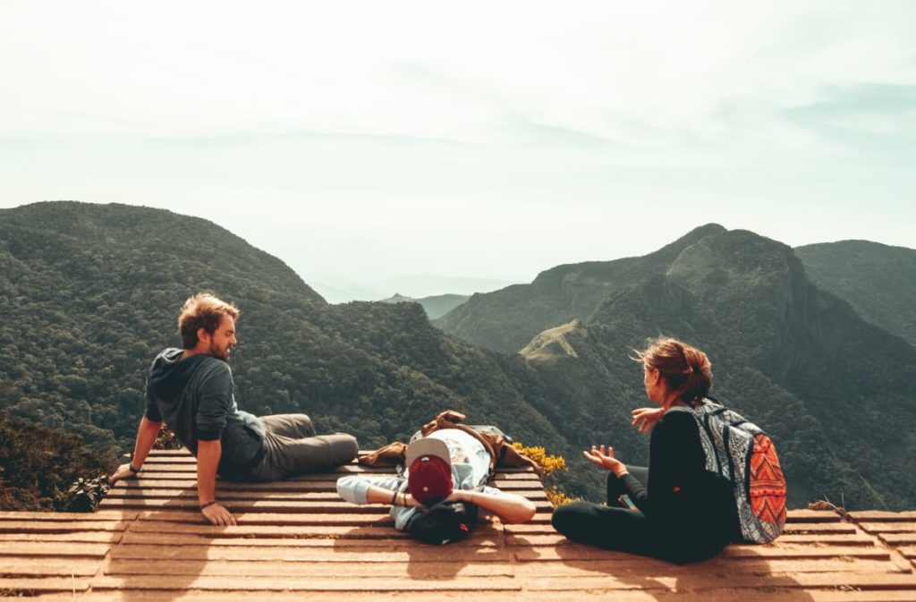 group of people sat on a viewing platform in the mountains