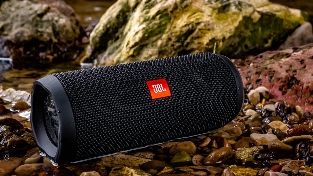 Black JBL speakers lying in a pond of water. 