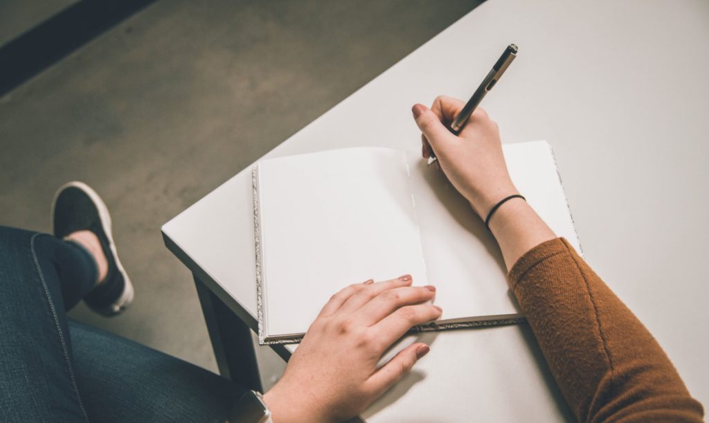 person sitting down with notepad and pen, ready to write in the notepad to create a plan