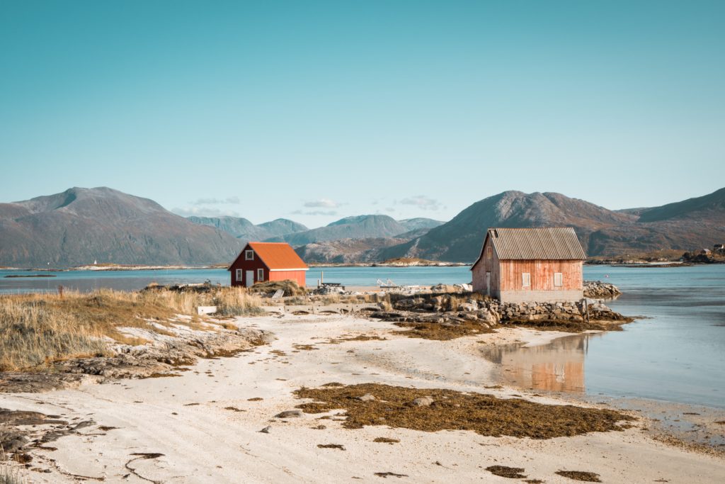 Tromsö, a city in the north of Norway, with mountains and snow in the background and a crystal clear lake next to the two small houses during easter